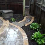 A stone walkway leading through a fence