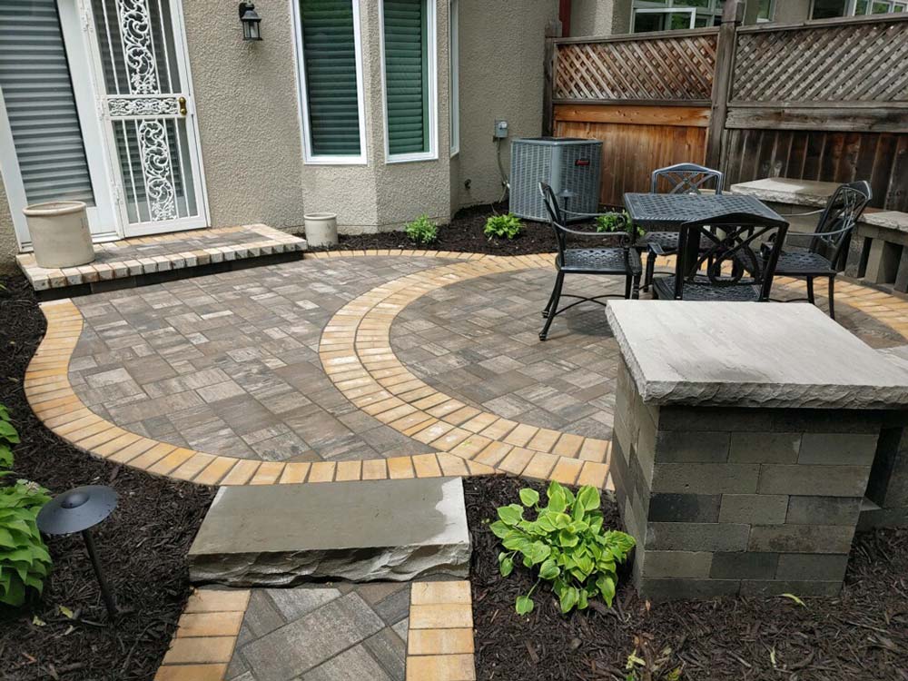 A stone patio with a table and seating on it