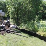 Machinery digging a barrier between apartments and a pond